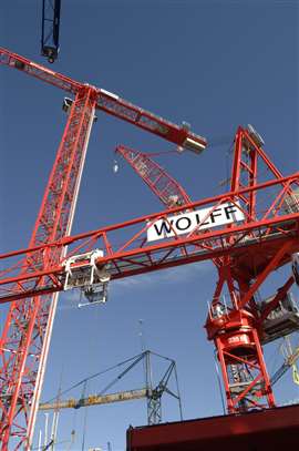 red Wolff tower cranes against a blue sky