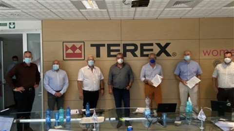 Lineup of people in masks below Terex logo in office