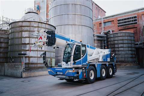 Blue and white mobile crane standing in travel position in an industrial setting