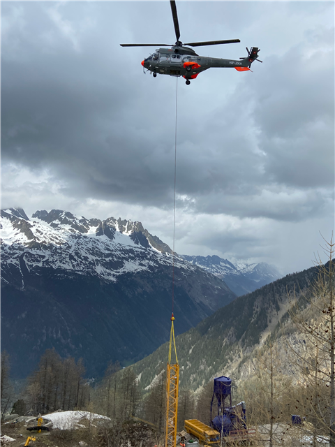 A helicopter transports part of a Potain MDT 109 crane over the French Alps
