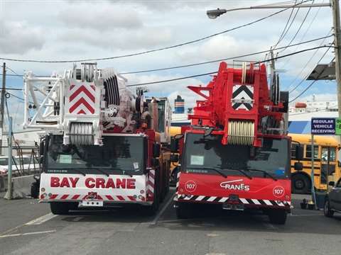 white Bay Crane and red Cranes, Inc. crane side by side